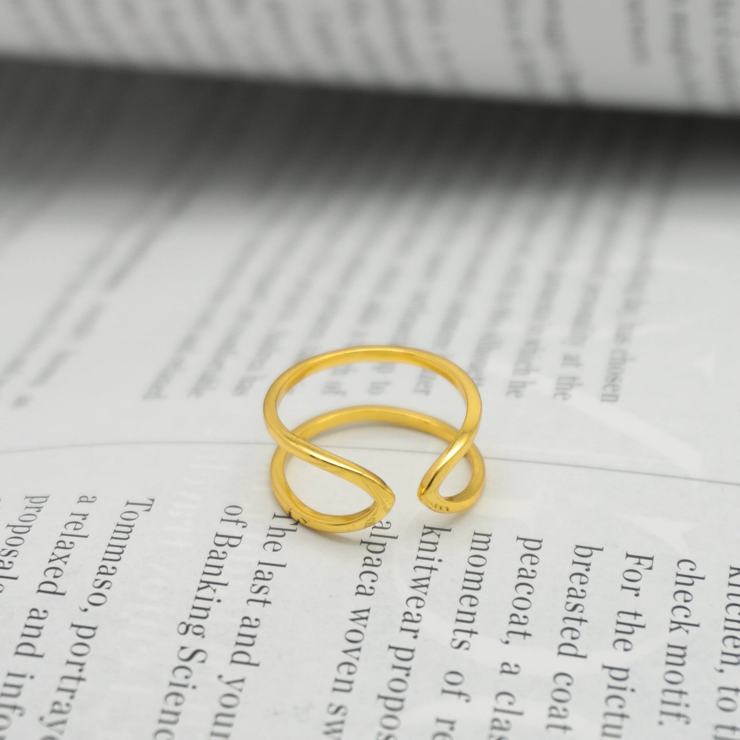 Anillo de plata bañado en oro Celessta sobre las páginas de un libro.